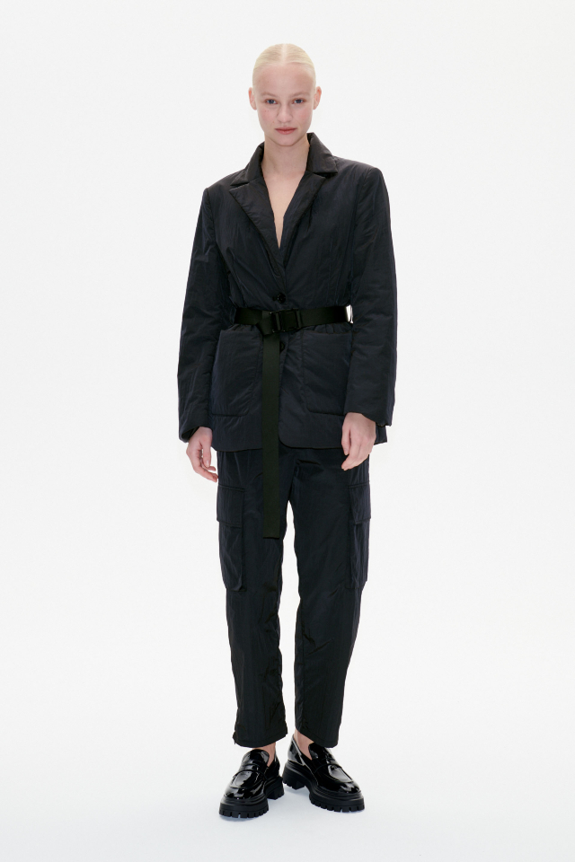 Nemu Trousers Black These high-rise, nylon trousers feature an elasticated waistband with a drawstring, zip pockets at the sides, cargo pockets on the legs, and zips at the ankles - model image