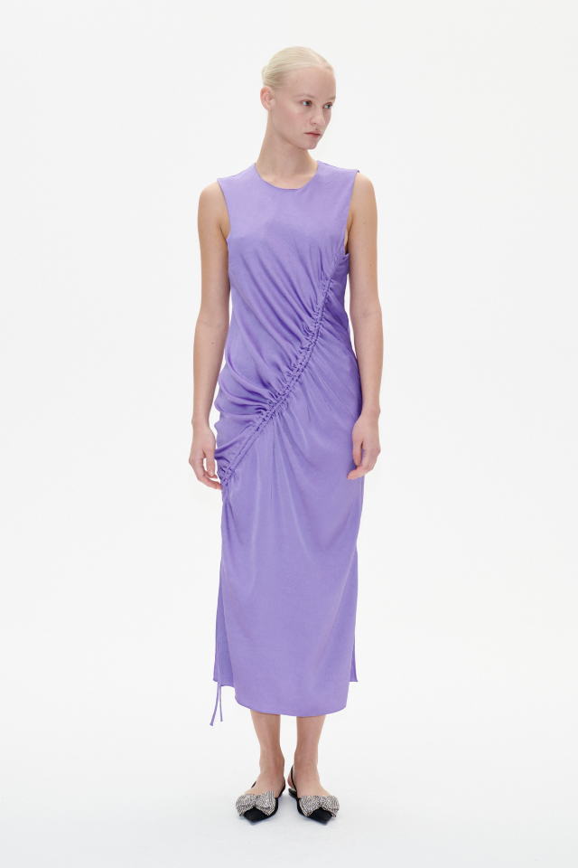 Allanna Dress Dahlia Purple This midi-length, sleeveless dress features a button closure with keyhole opening in the back and ruching with an asymmetrical drawstring across the front - model image