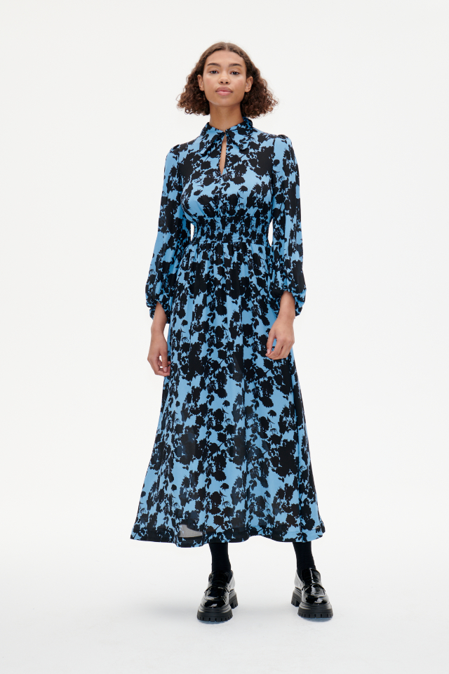 Amber Dress Blue Flower Jacquard This collared maxi dress features a button closure at the neckand stretchy smocking at the waist for a comfortable fit - model image